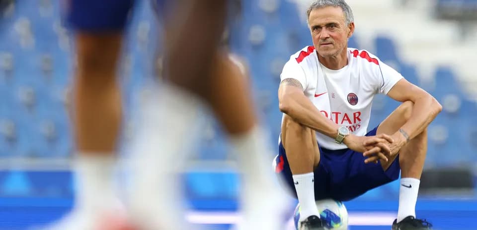 Coach squatting on pitch during training session