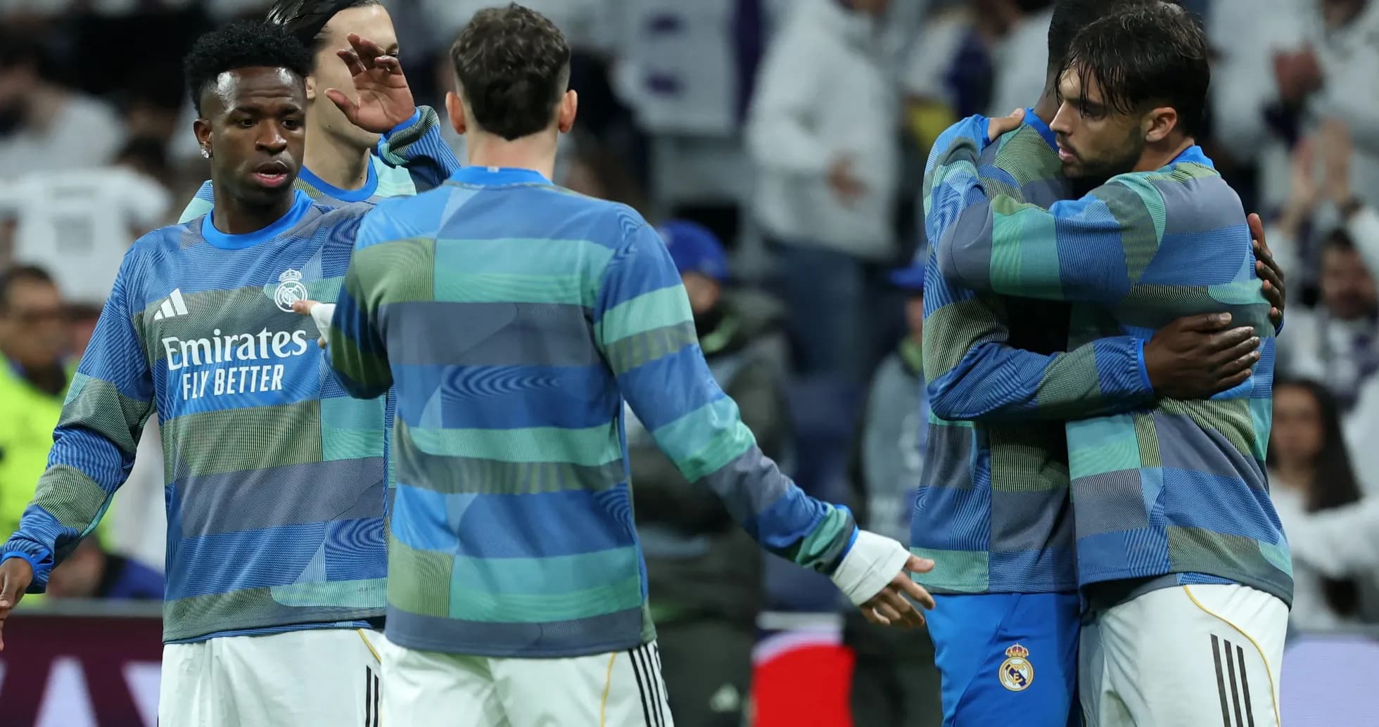 Real Madrid players in warm-up jerseys embracing
