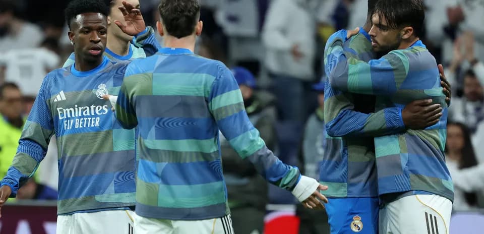 Real Madrid players in warm-up jerseys embracing