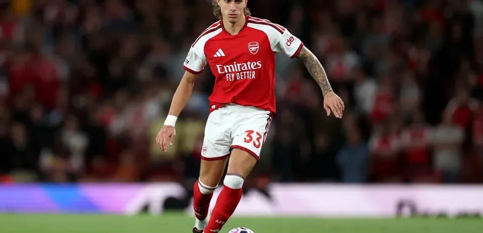 Player in Arsenal kit dribbling the ball
