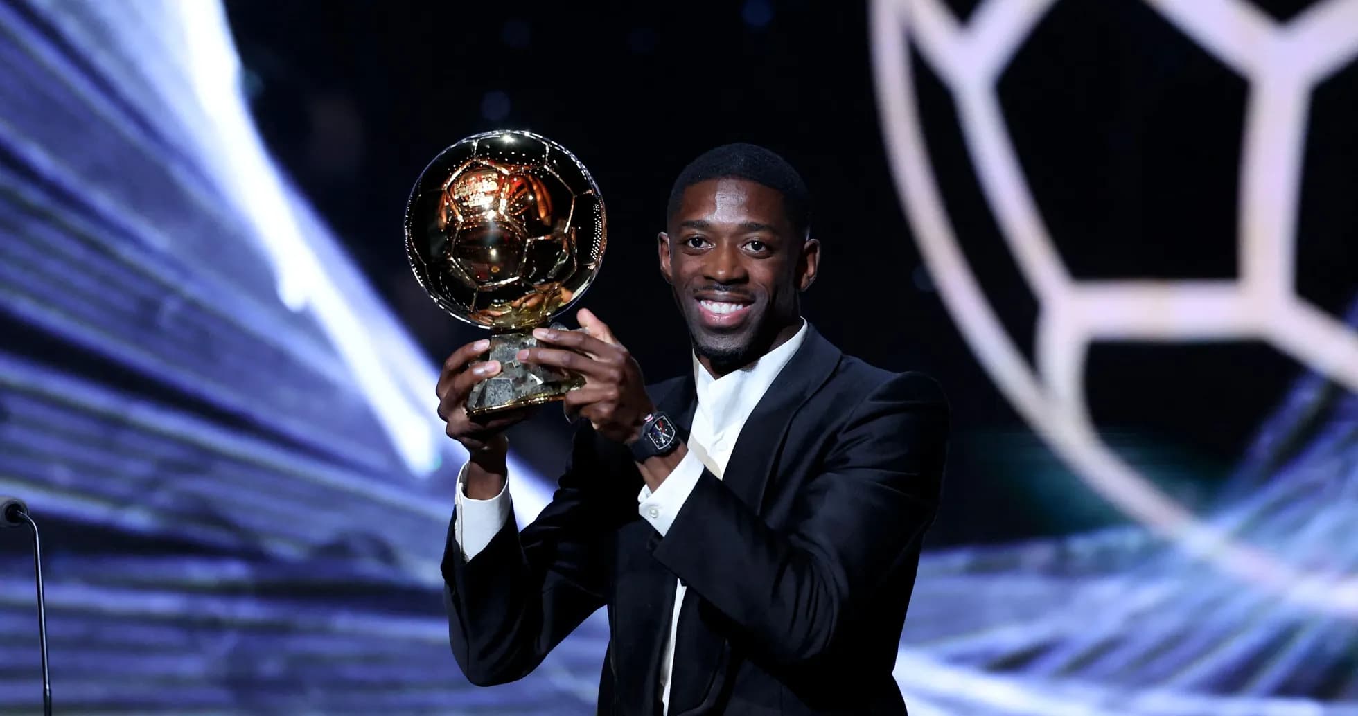 Player holding Ballon d'Or trophy on stage