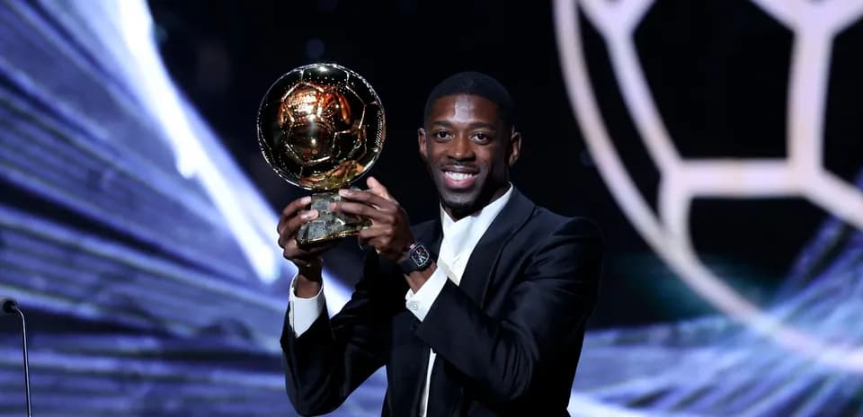 Player holding Ballon d'Or trophy on stage