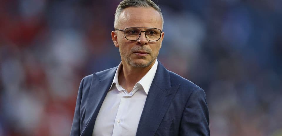 Man in suit with glasses on the sidelines