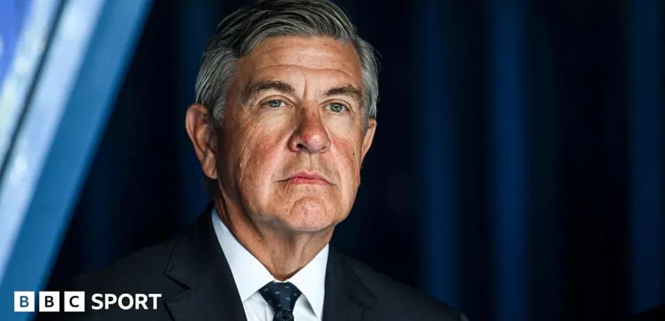 Man in suit standing in front of blue backdrop