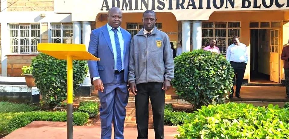 Two individuals posing outside St. Anthony's Boys' High School
