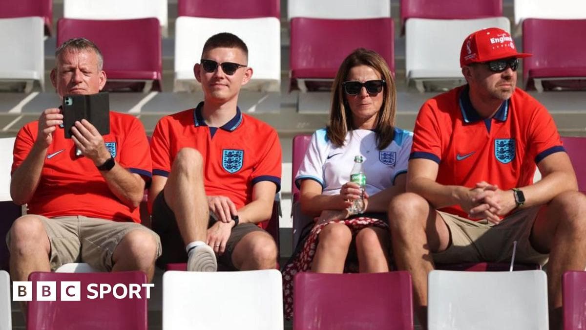 Fans wearing England jerseys sitting in stadium seats