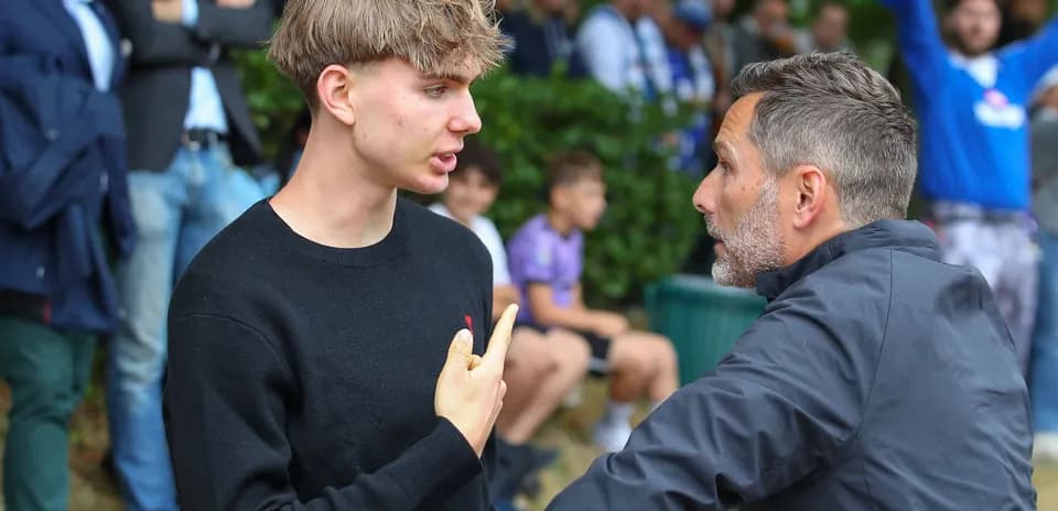 Young man and adult discussing near spectators