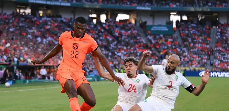 Player 22 of Netherlands evading two Moroccan defenders