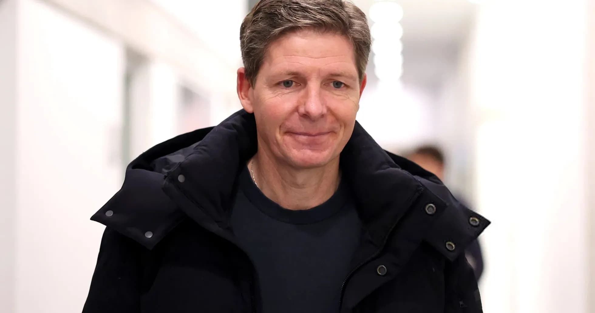 Person walking in a corridor wearing a dark jacket
