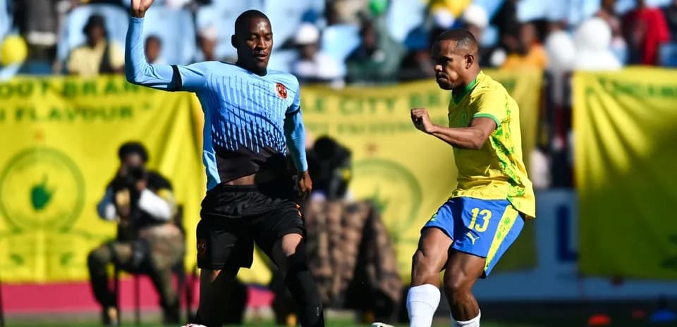 Player in yellow kicking ball, opponent defending