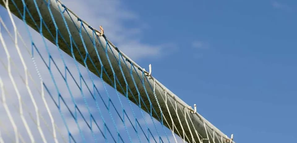 Close-up of a soccer goal net against blue sky