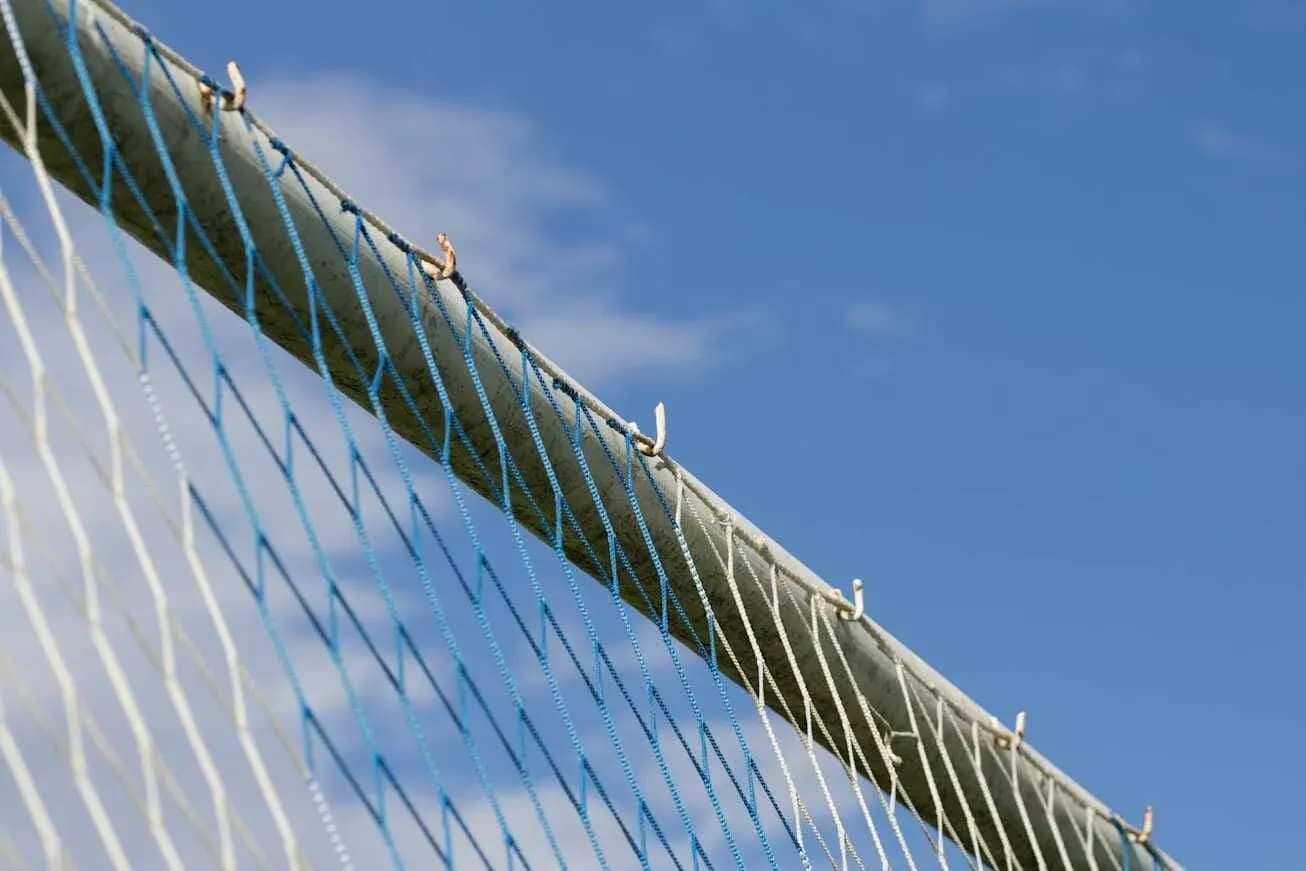 Close-up of a soccer goal net against blue sky