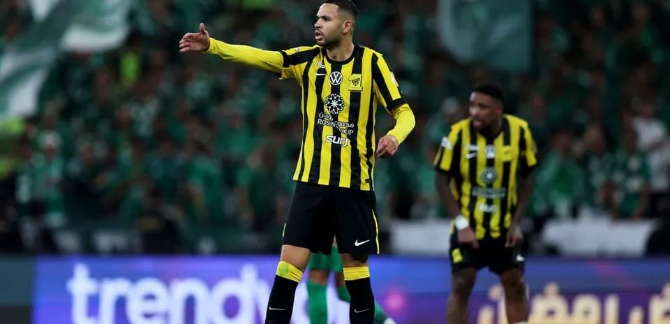 Player directing teammates during match with supporters behind