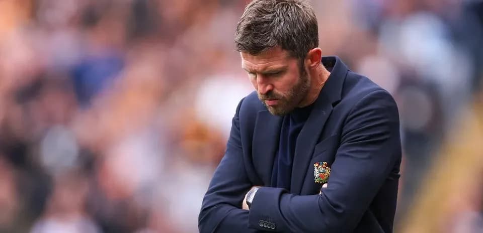 Manager looking down with arms crossed during match