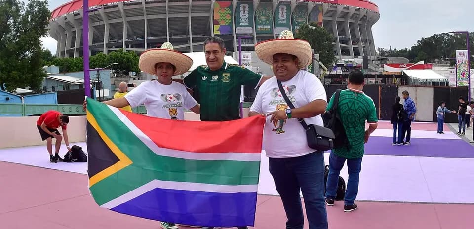 Fans posing with South African flag outside stadium