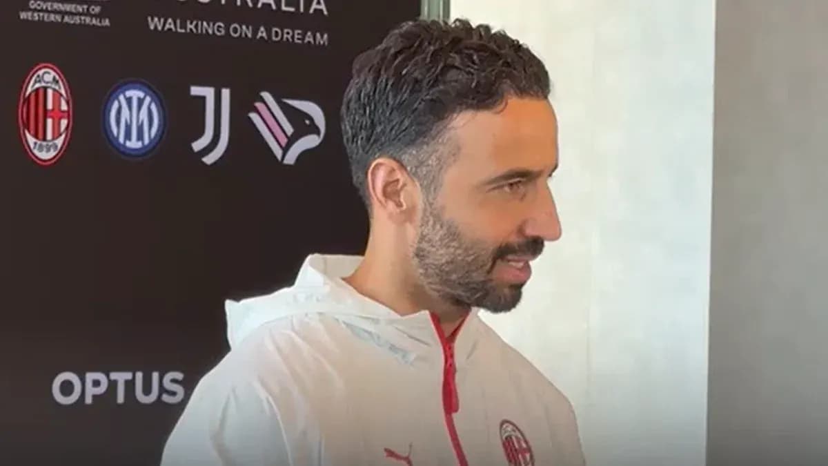 Person speaking at press conference with team logos