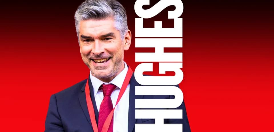 Smiling man in suit with red tie and lanyard