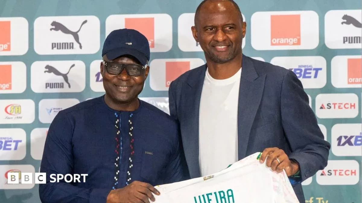 Two men holding a football jersey at a press event