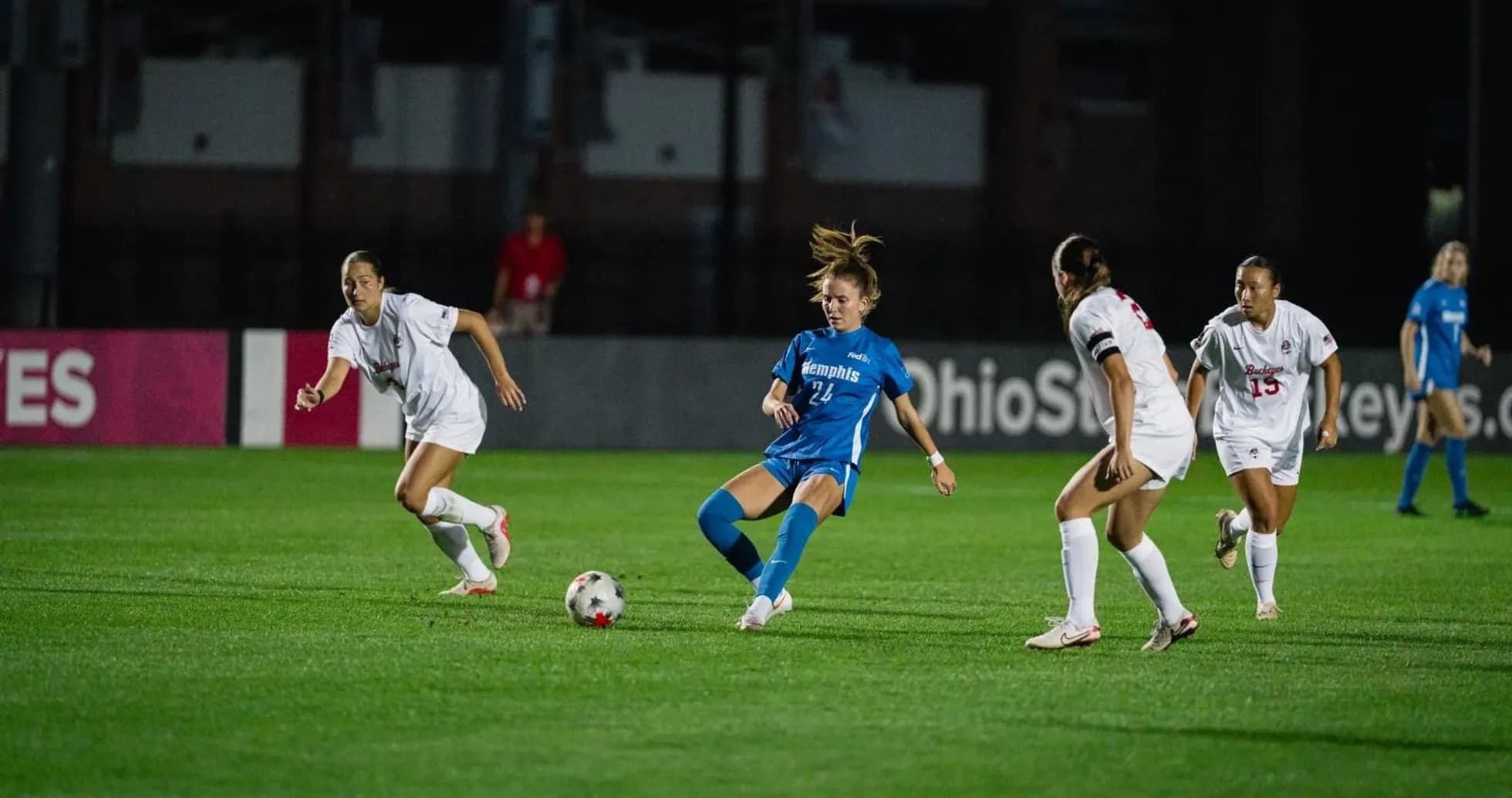Player in blue dribbling past defenders in white