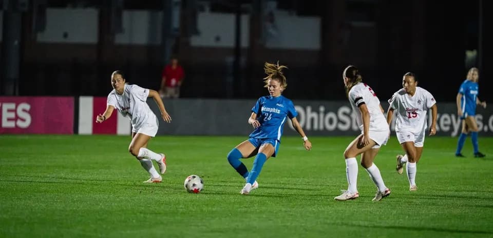 Player in blue dribbling past defenders in white