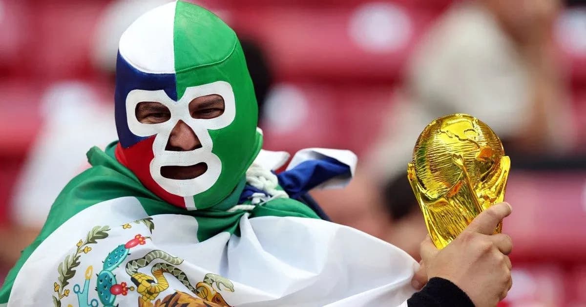 Fan wearing mask and holding World Cup trophy