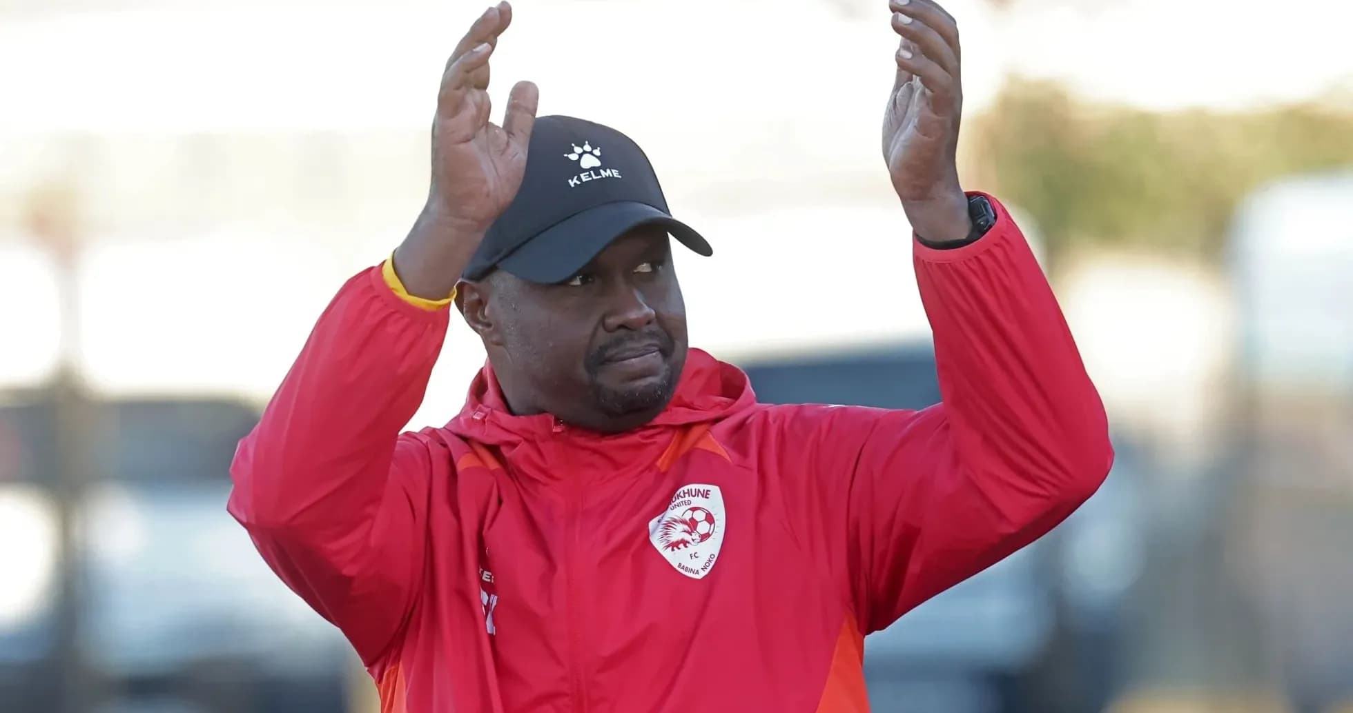 Coach gesturing during training session in red jacket