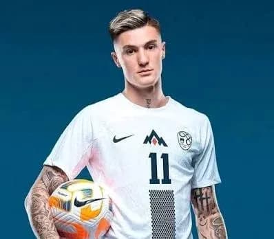 Player posing with soccer ball in team uniform