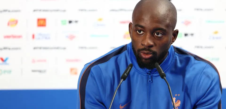 Player speaking at press conference with microphones