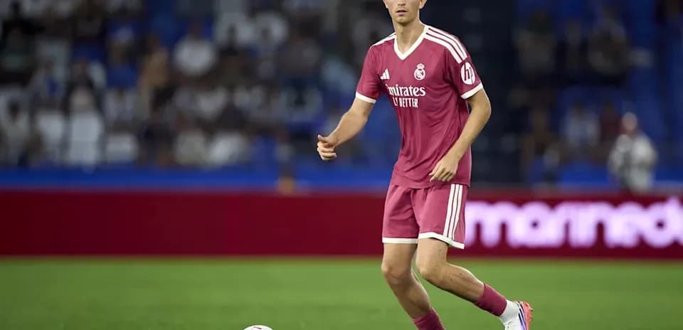 Player in pink kit dribbling ball on pitch