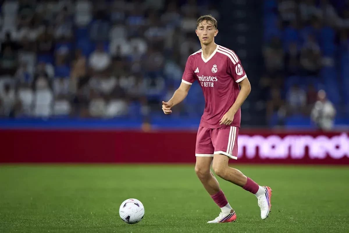 Player in pink kit dribbling ball on pitch