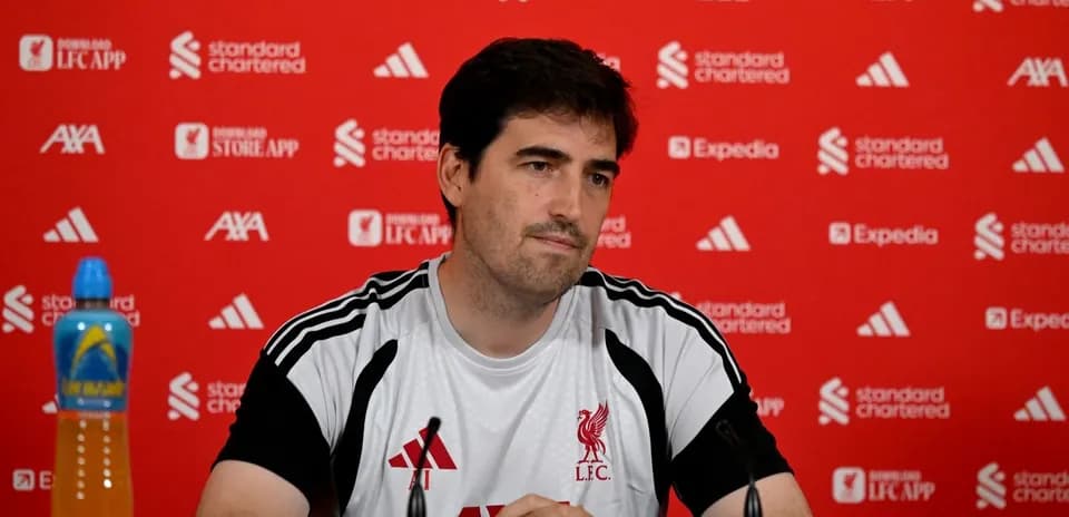 Coach at press conference with Liverpool branding backdrop