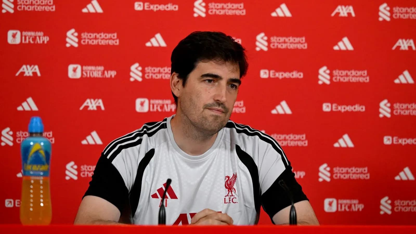 Coach at press conference with Liverpool branding backdrop