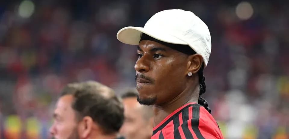 Player in red jersey observing from the sidelines
