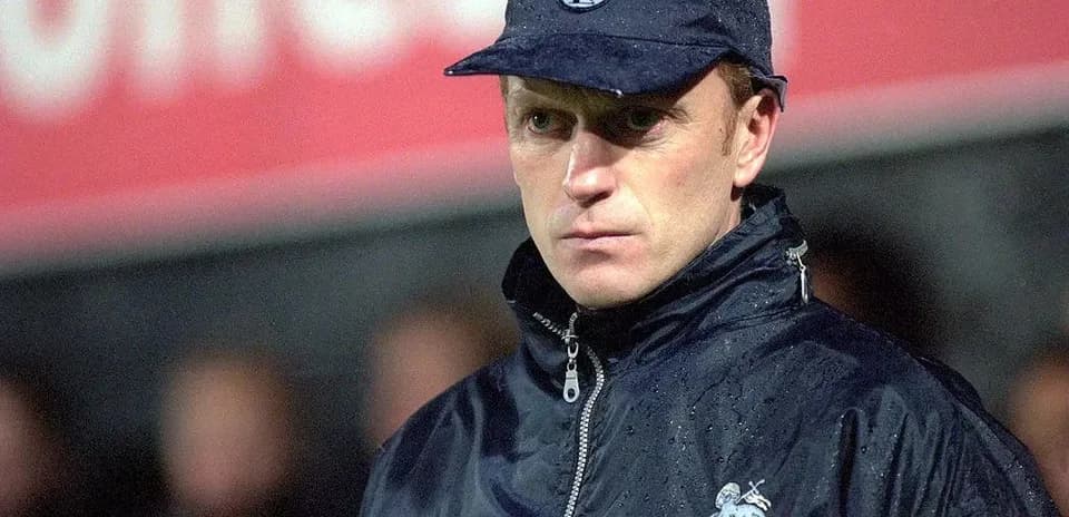Manager observing match in rain with cap