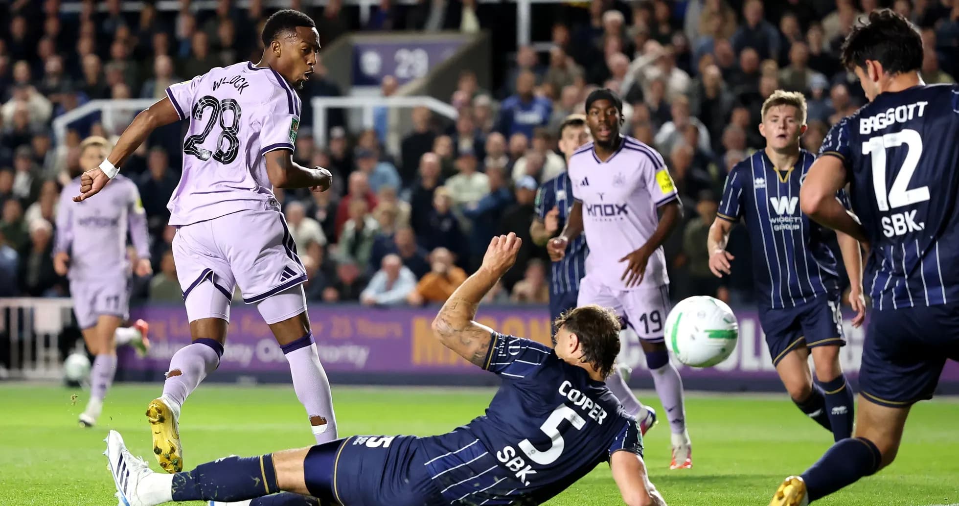 Player shooting at goal while defender falls