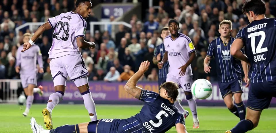 Player shooting at goal while defender falls