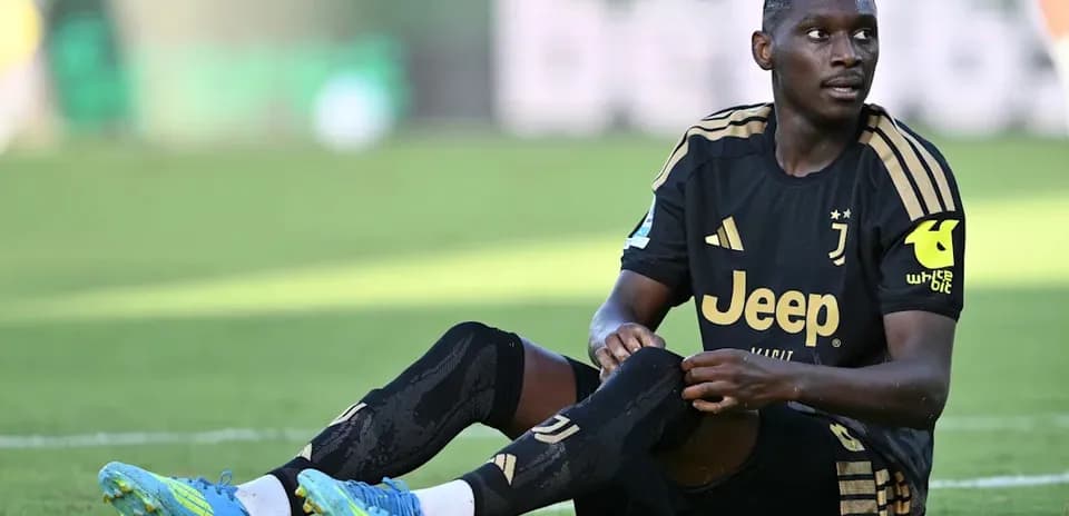 Player sitting on field wearing Juventus kit
