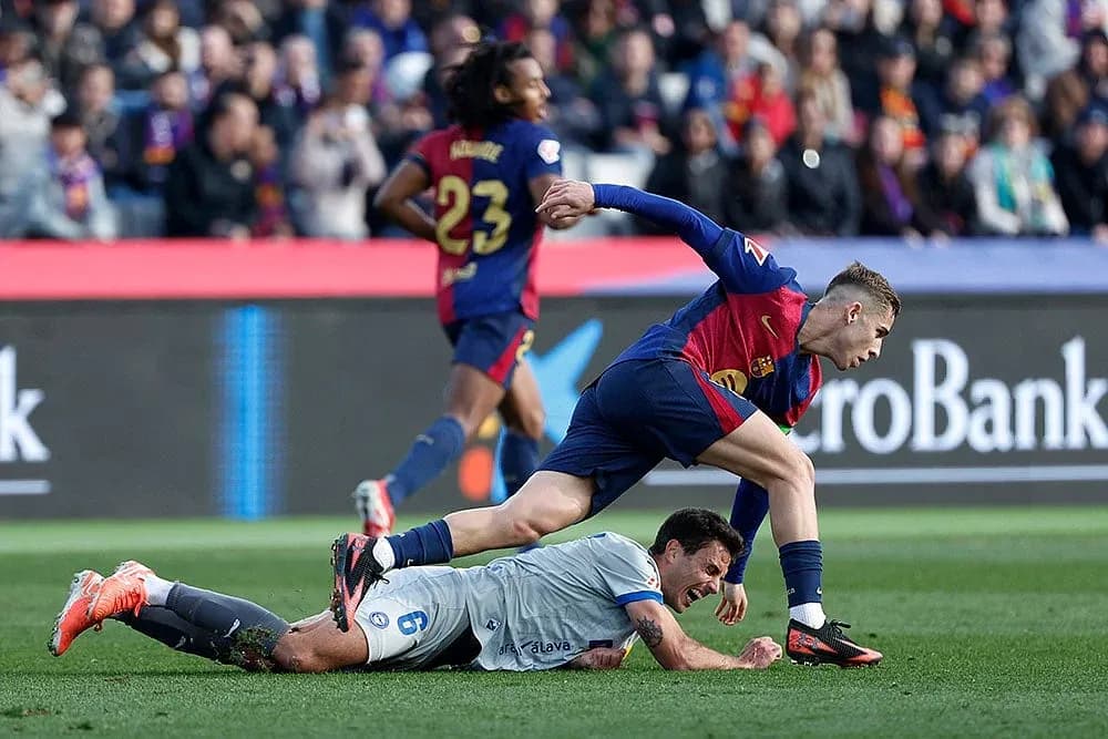 Barcelona player tackling Alaves goalkeeper during match