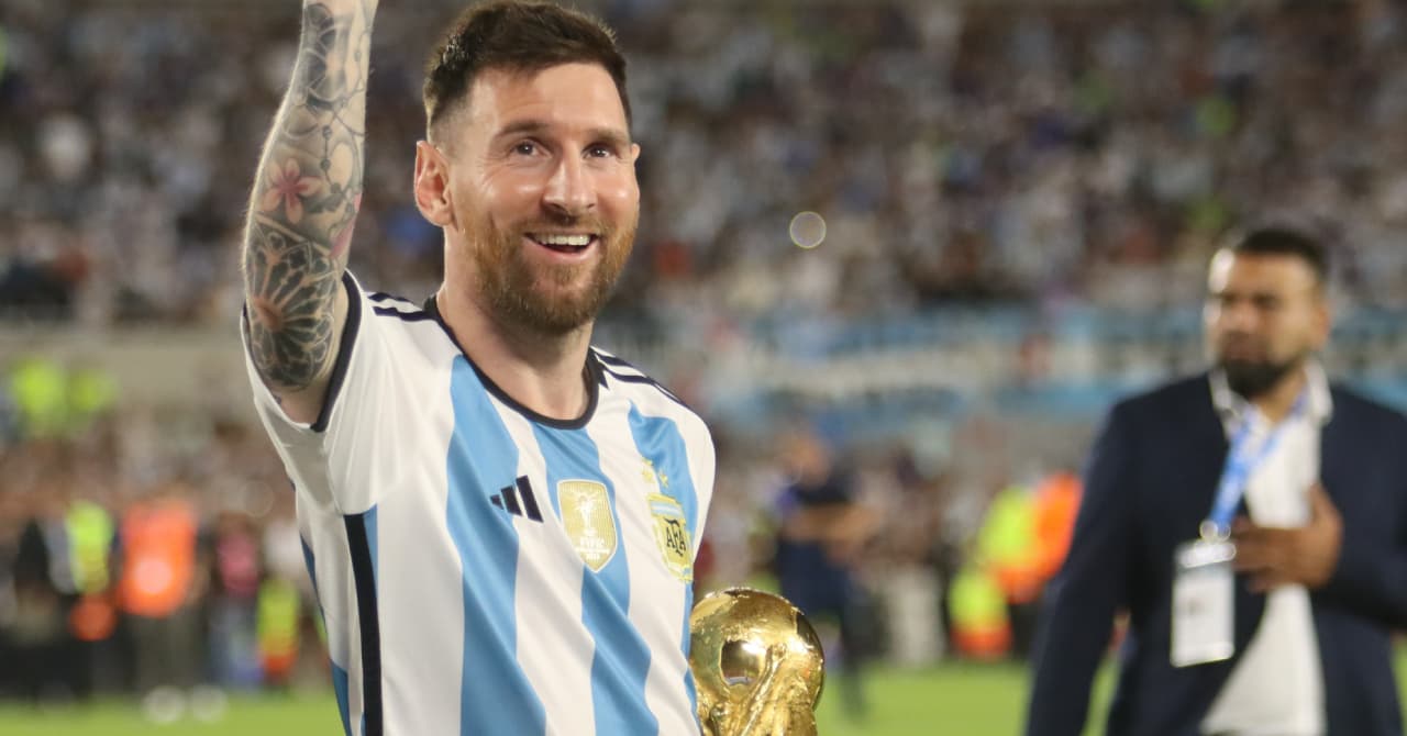 Player celebrating with World Cup trophy in stadium