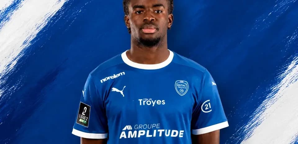 Player in blue ESTAC Troyes jersey against blue background