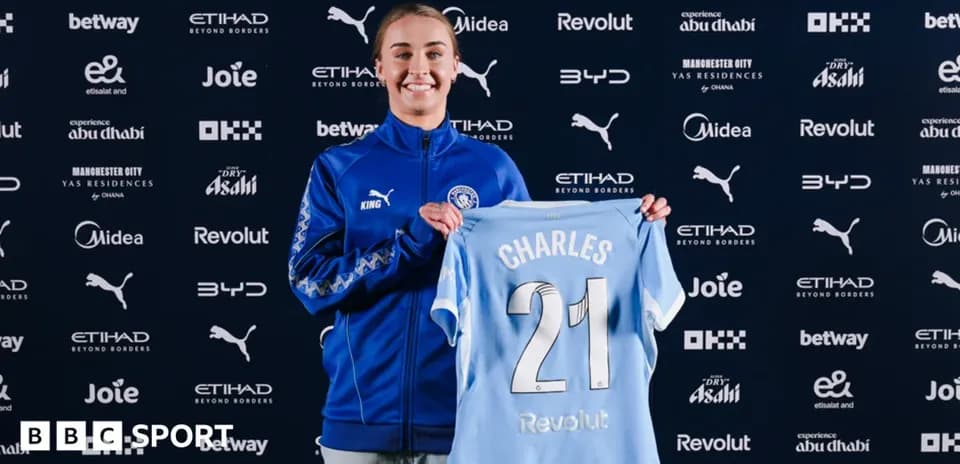 Player holding Manchester City jersey at press conference