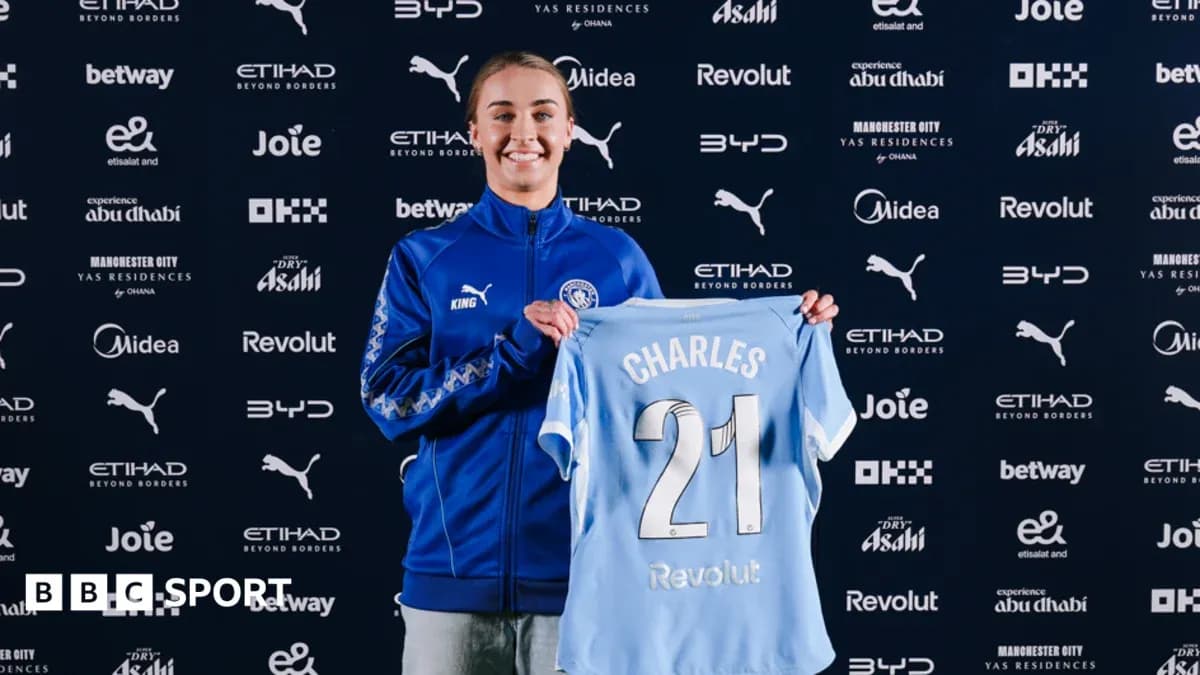 Player holding Manchester City jersey at press conference