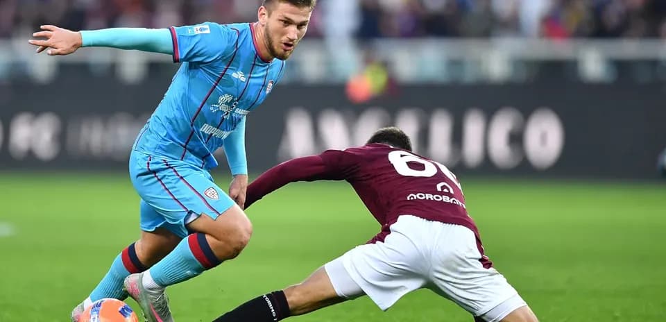 Cagliari player evading a tackle from Torino opponent