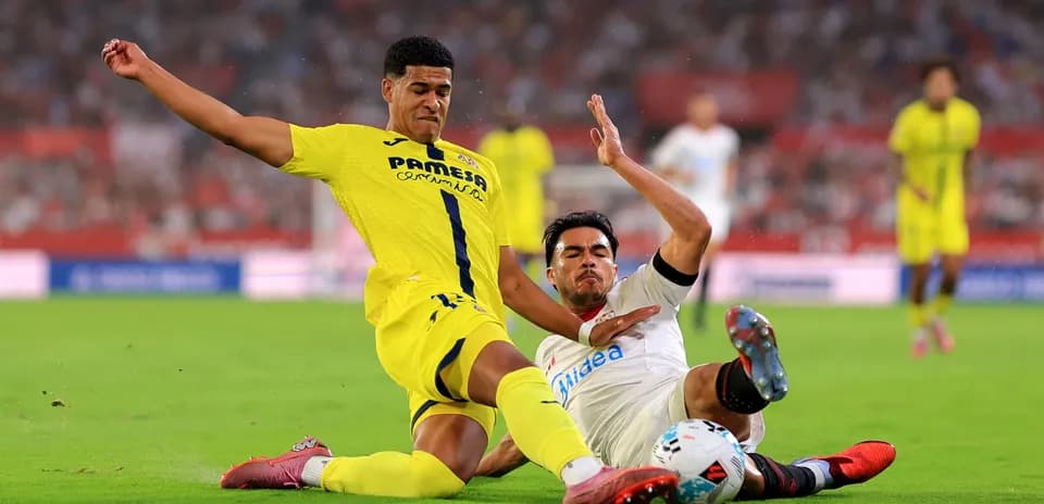 Villarreal player tackling Sevilla player during match
