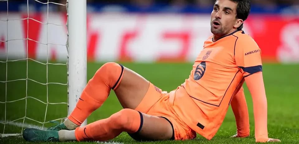 Goalkeeper sitting on the pitch near goalpost