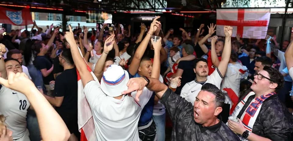Crowd of fans celebrating in a bar during match
