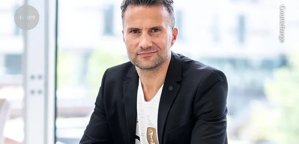 Man wearing a blazer, sitting indoors, smiling