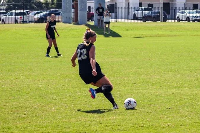 Player number 23 kicking soccer ball on field