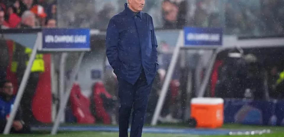 Coach standing on sidelines during rainy match