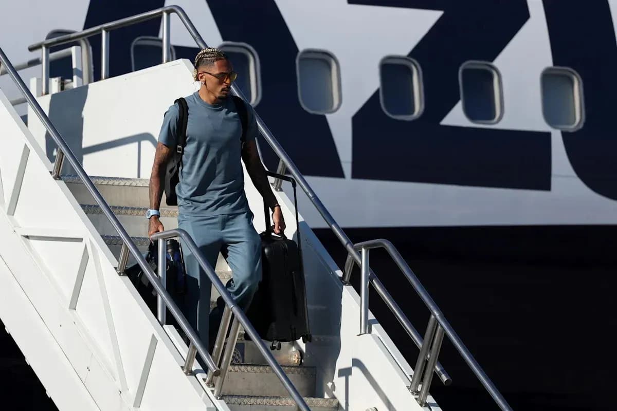 Player walking down airplane steps with suitcase